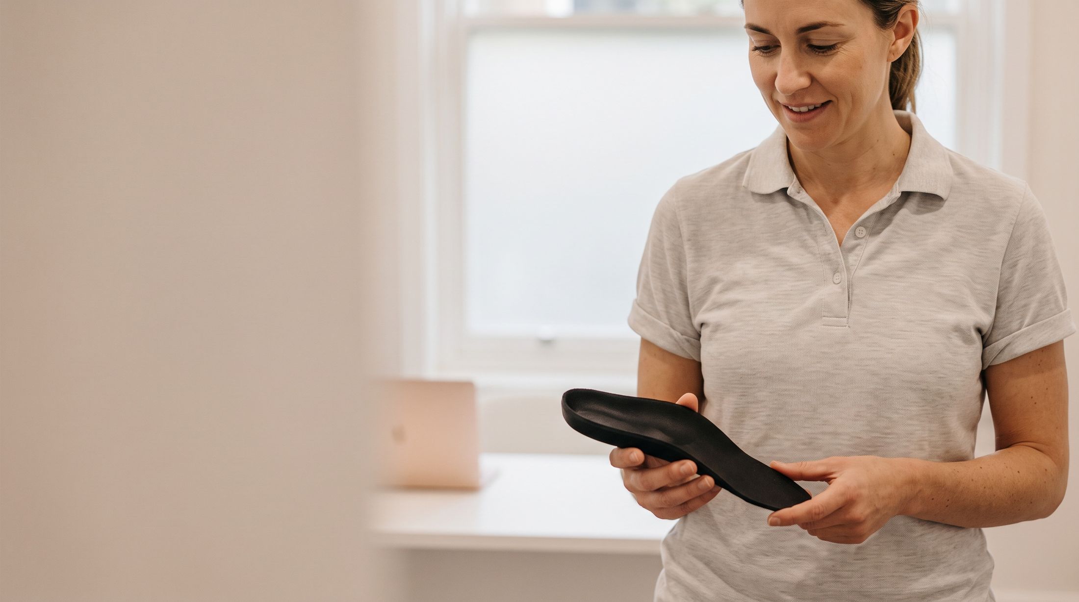 A clinician holding a custom orthotic ready for fitting